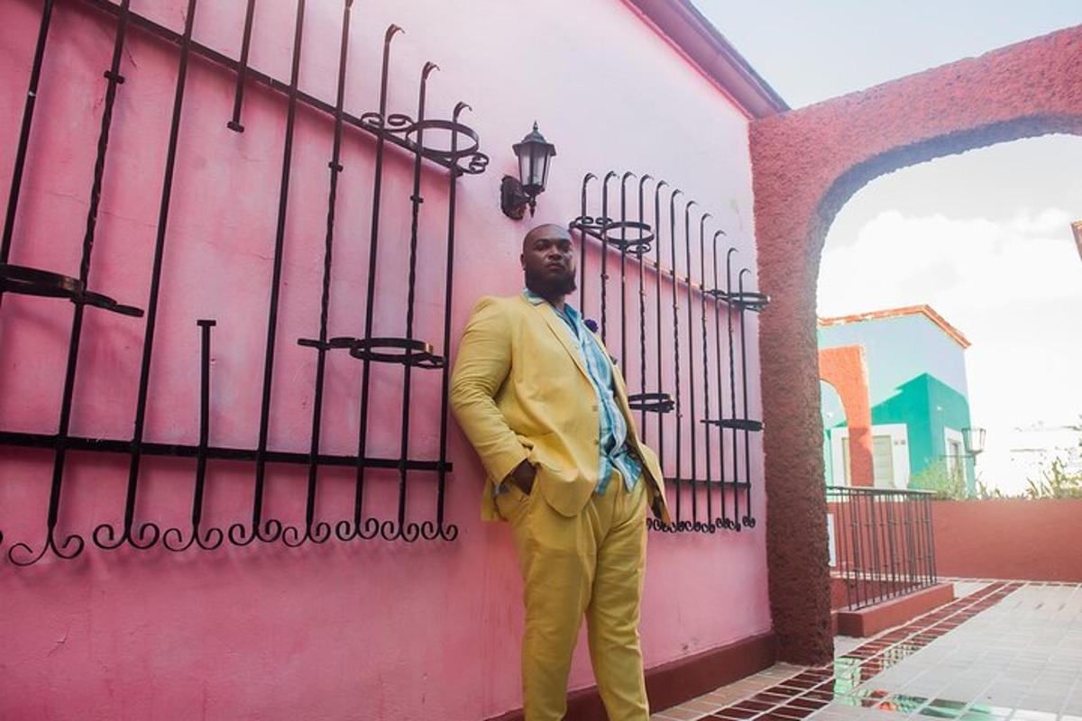 um homem de terno amarelo parado ao lado de uma cerca