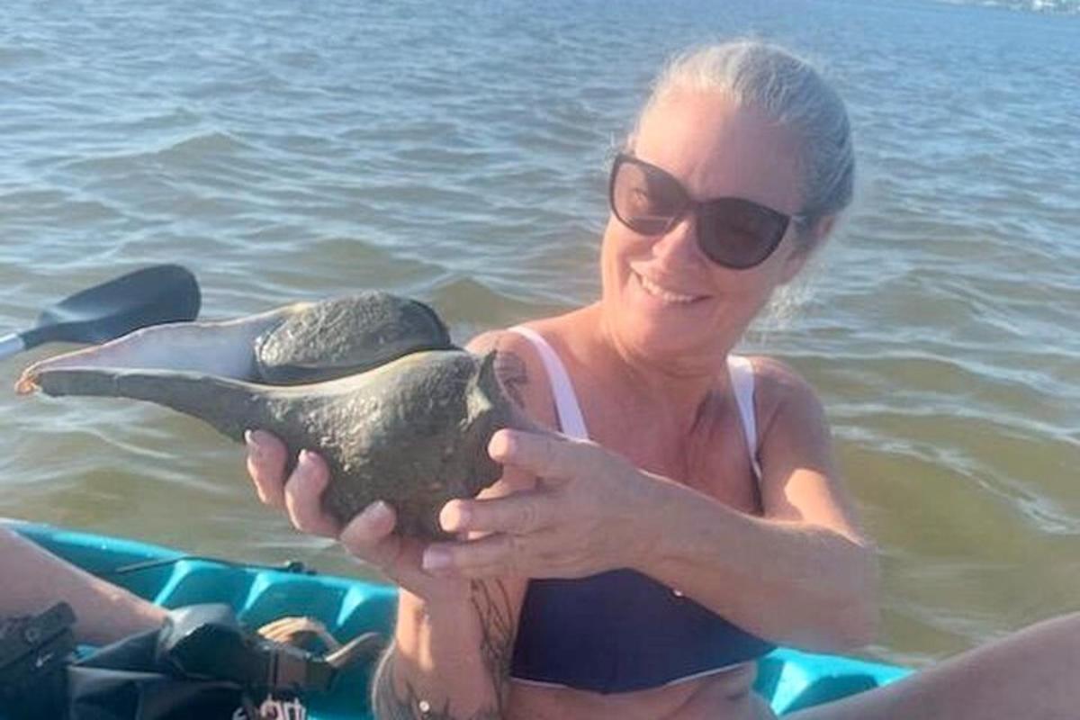 a woman in the water holding a turtle