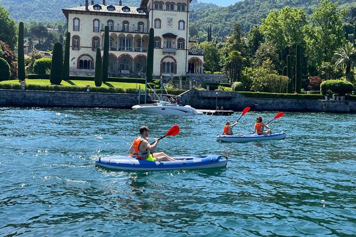 three people in kayaks on the water in front of a building