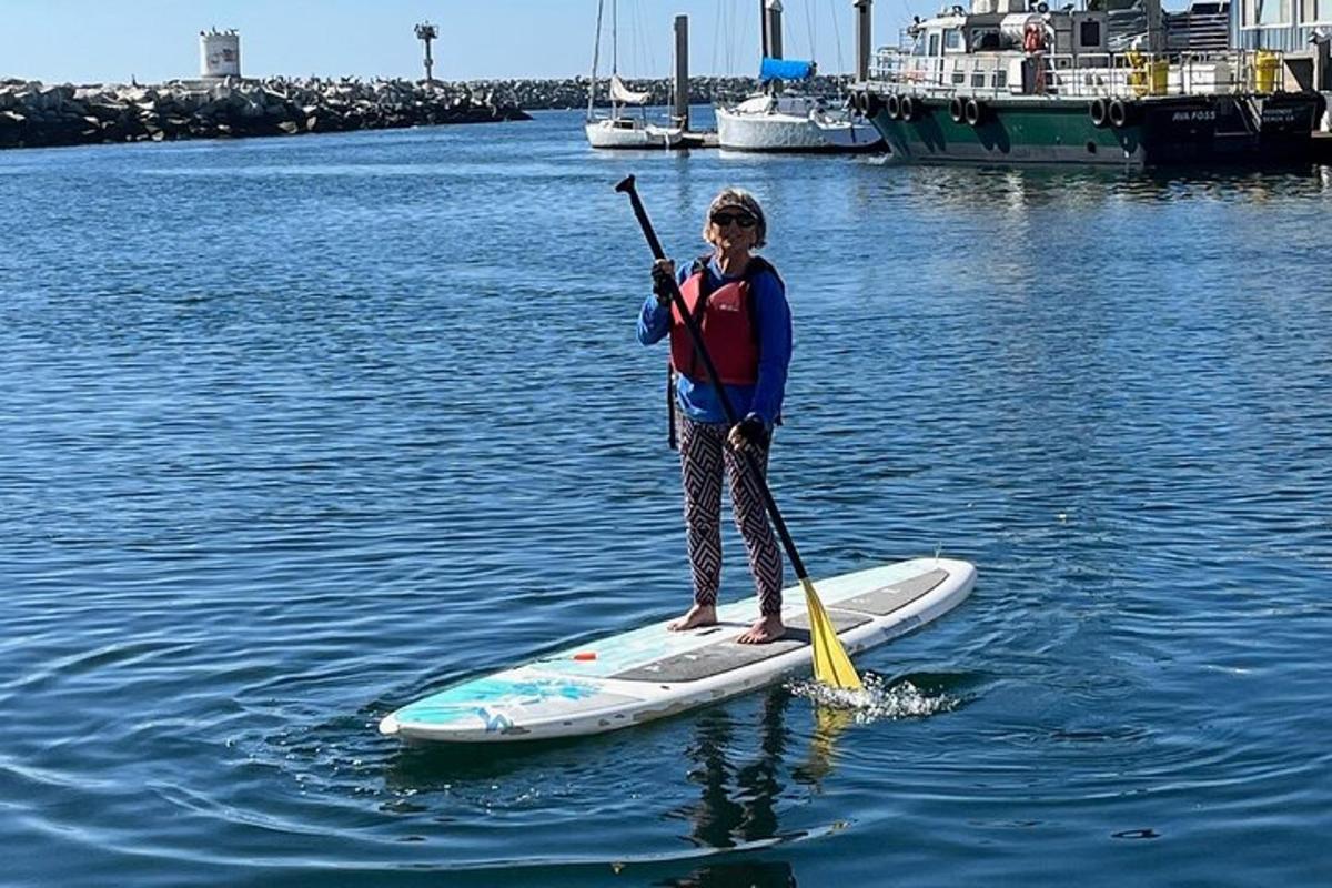 una donna in piedi su una tavola da paddle in acqua