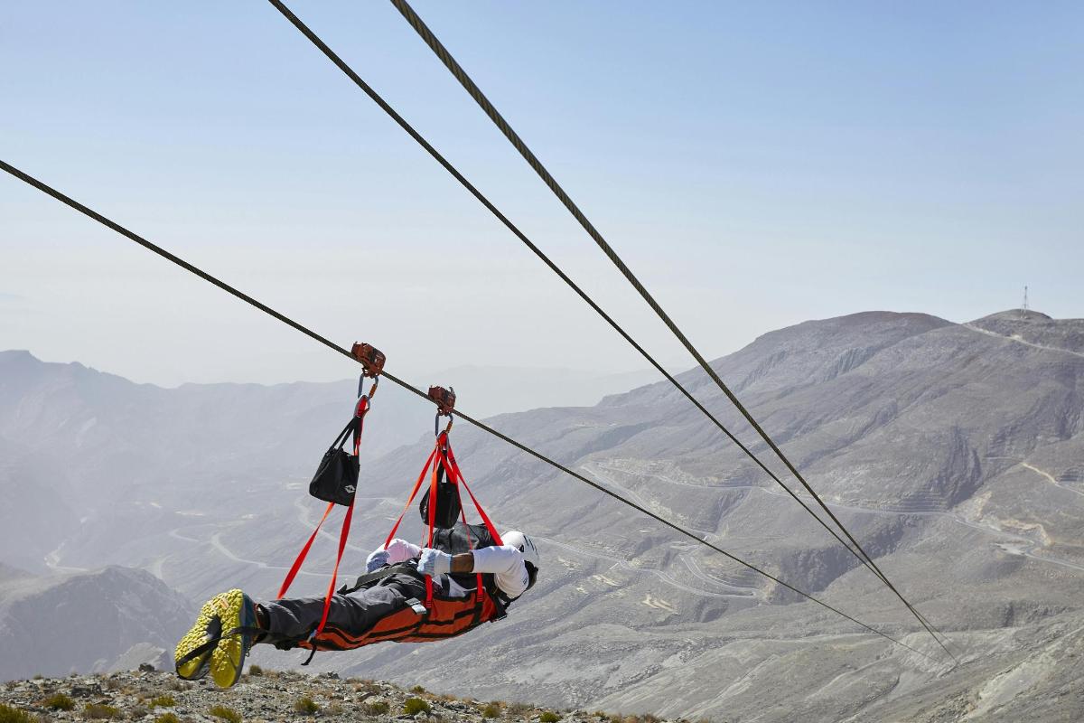 a person hanging on a zip line in the mountains