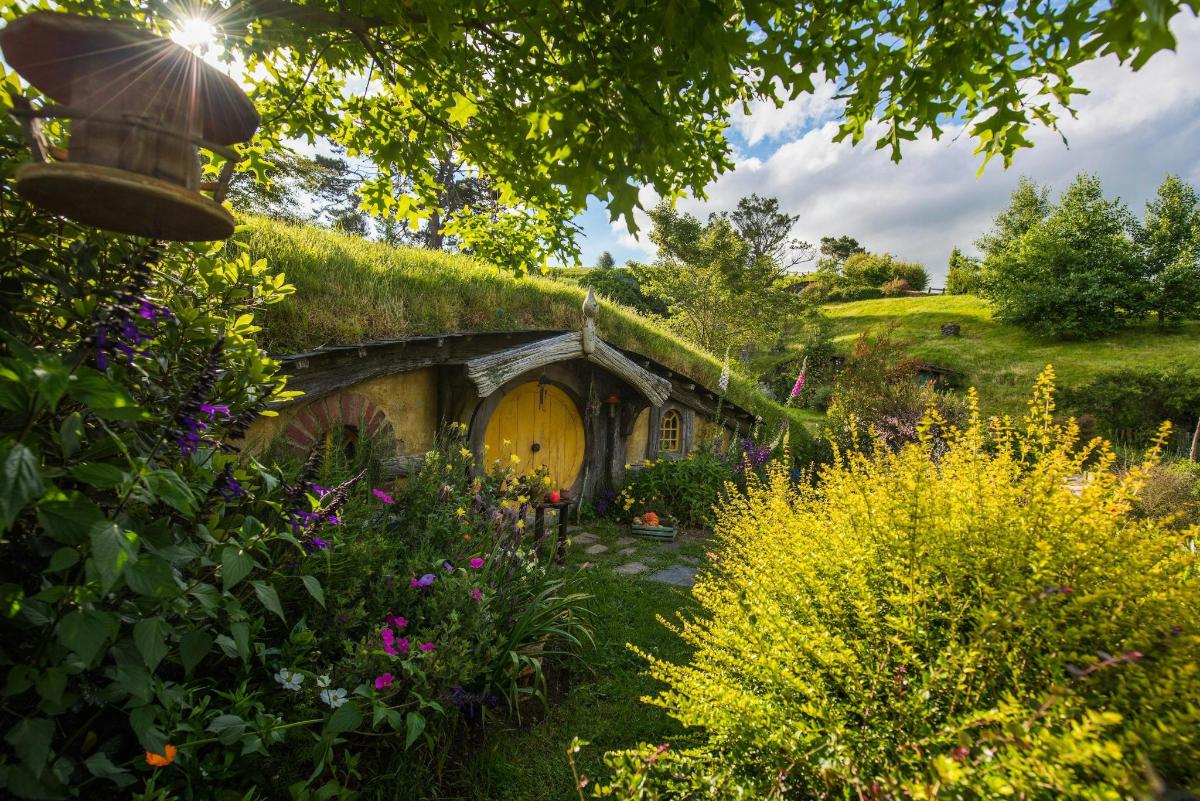 a house with a grass roof with flowers in a garden