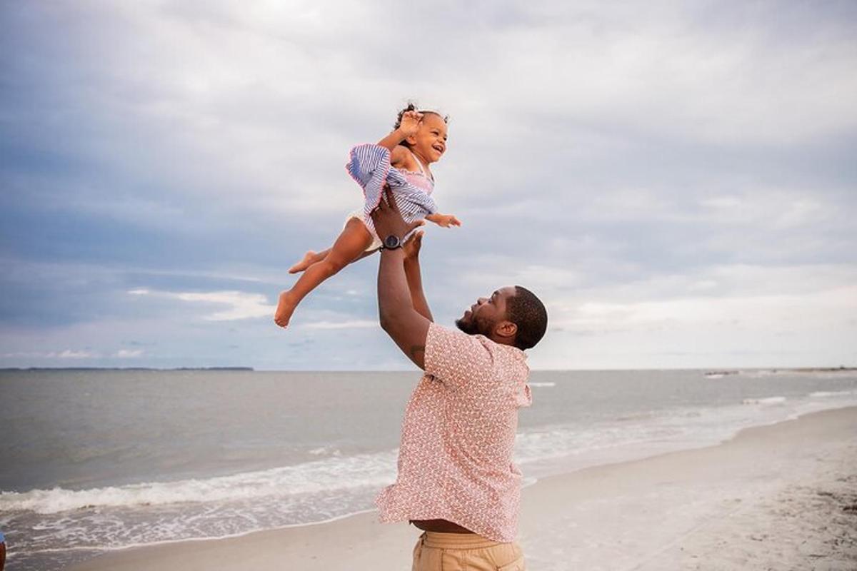 a man holding a little girl on the beach
