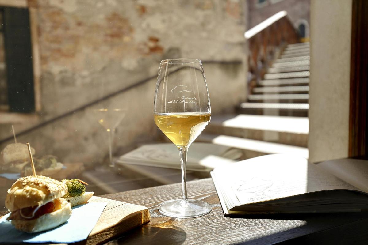 uma taça de vinho e um sanduíche em uma mesa