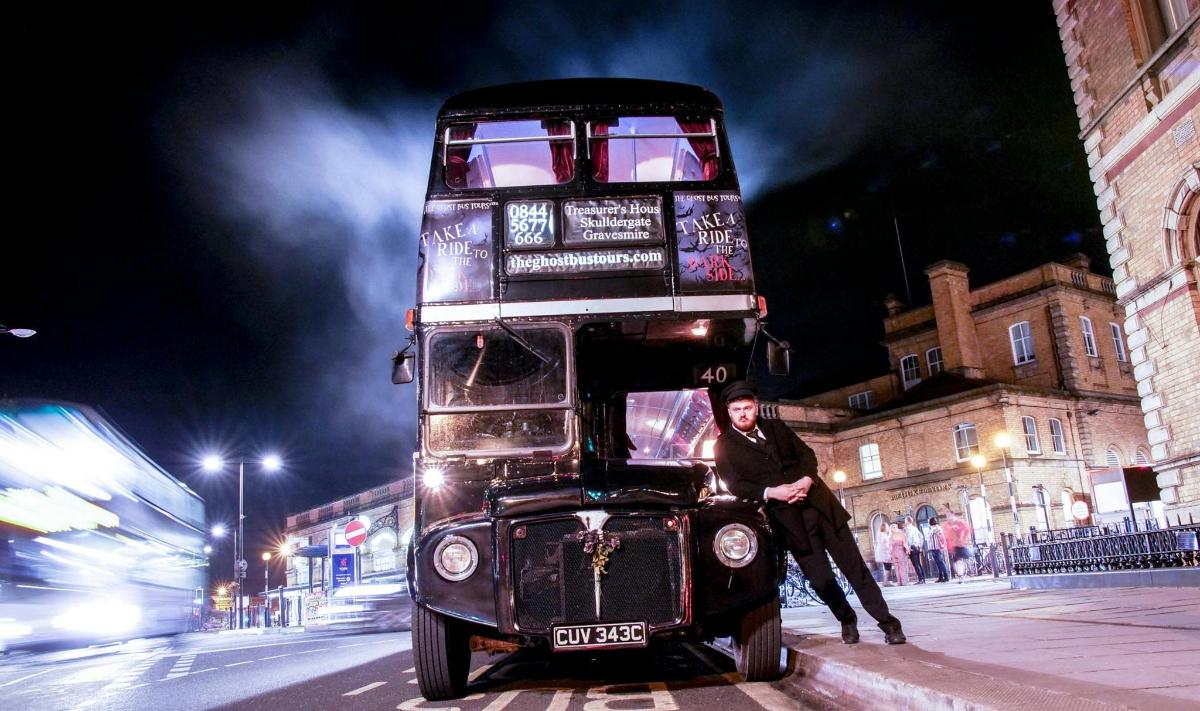 a man standing next to a double decker bus