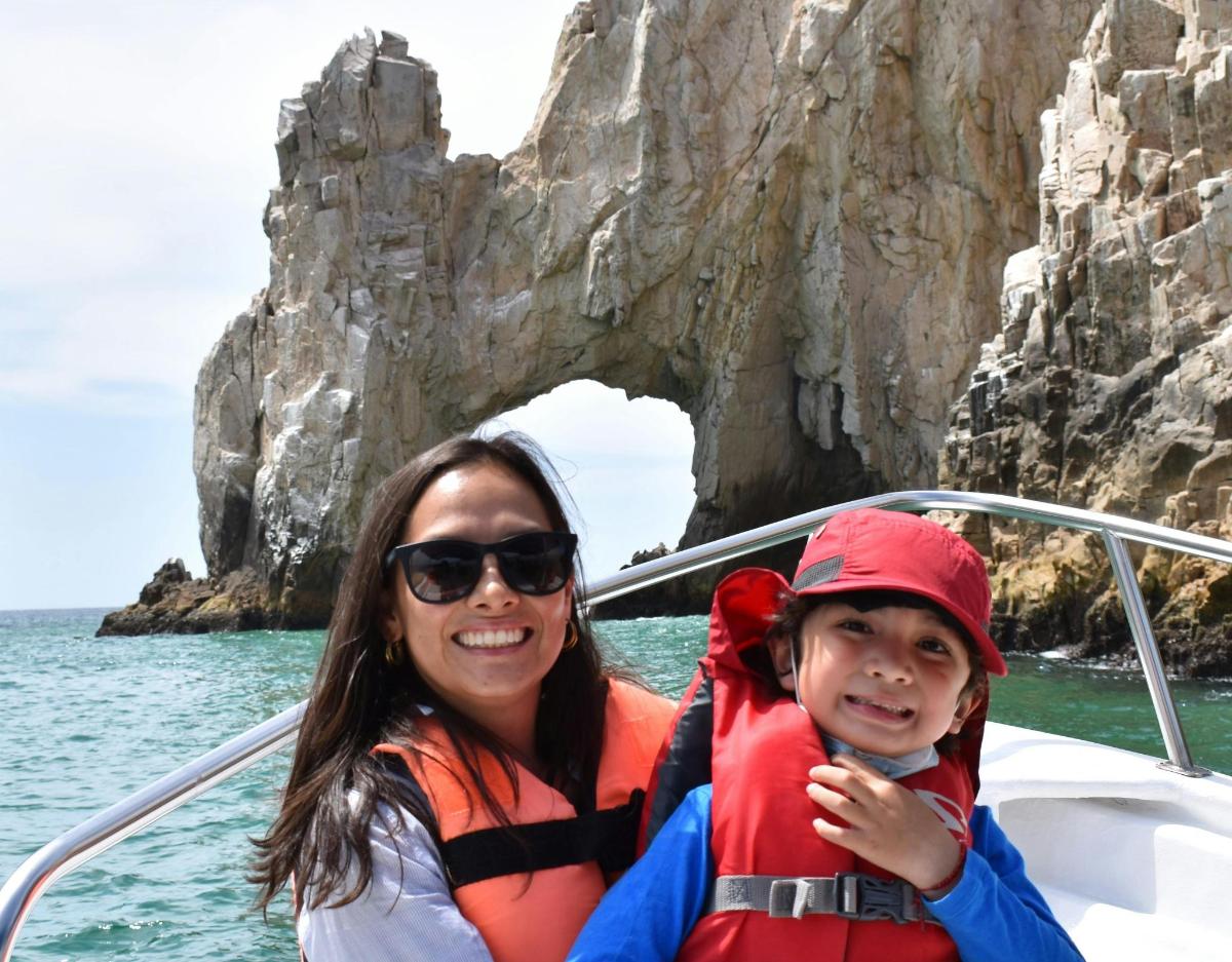 una donna e un bambino su una barca di fronte a una grotta