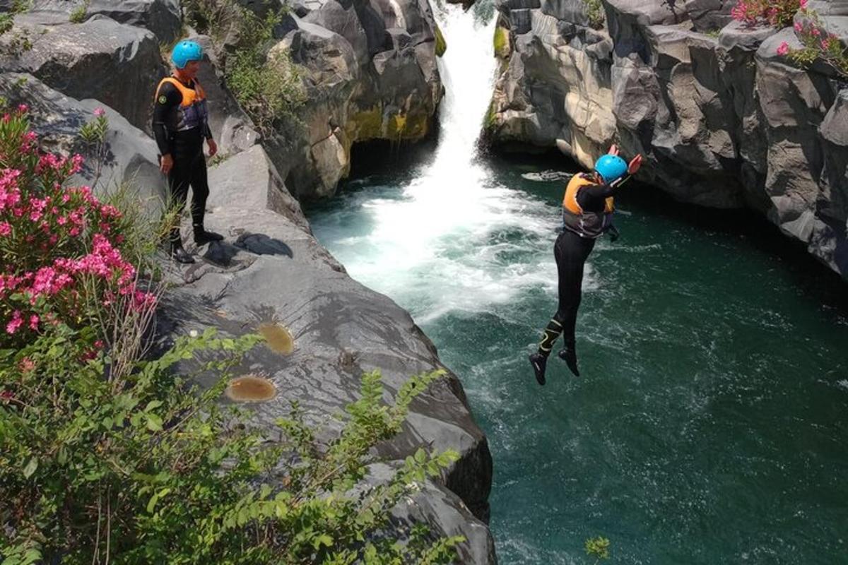 due persone che saltano in un fiume di fronte a una cascata