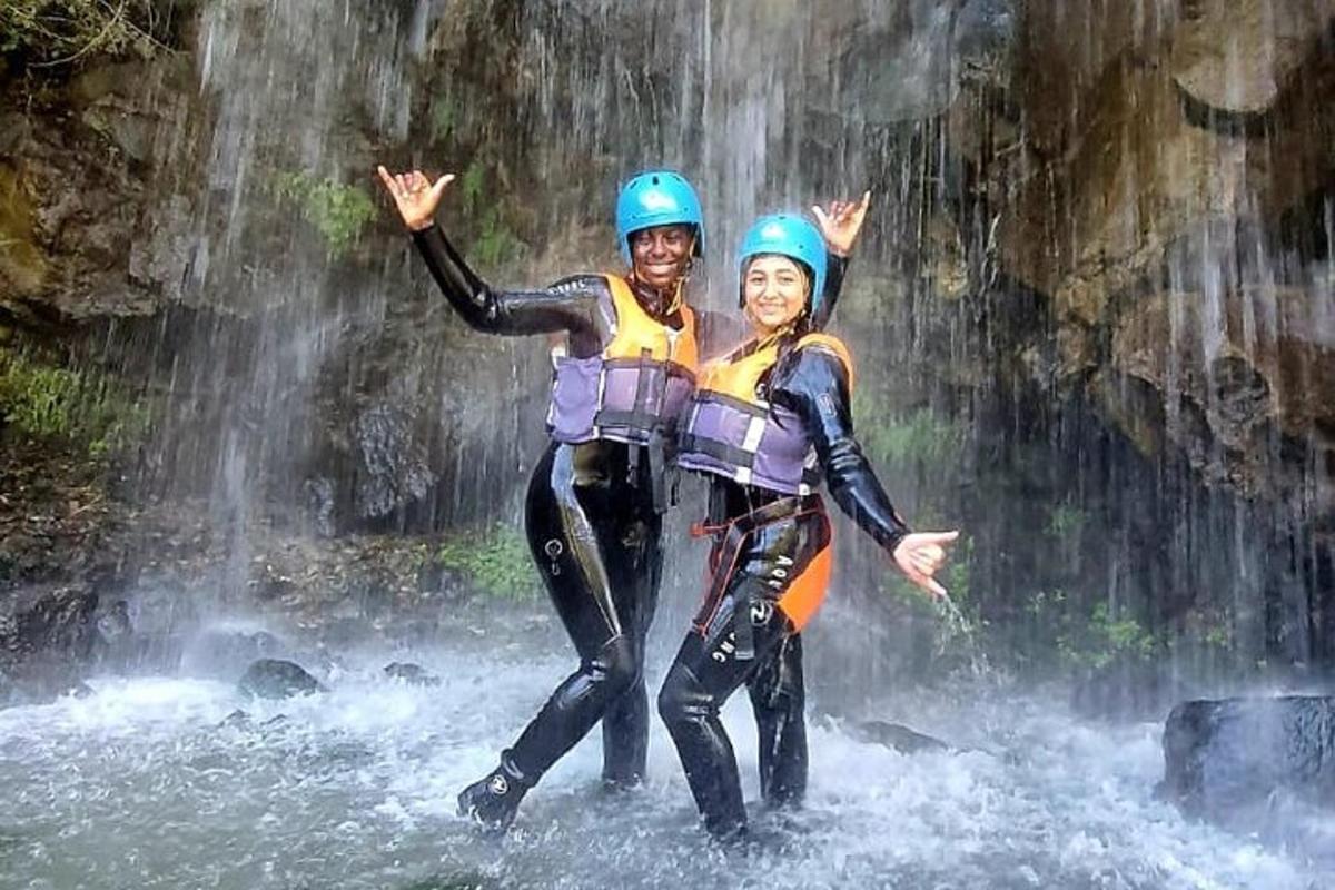dua orang berdiri di air di depan air terjun