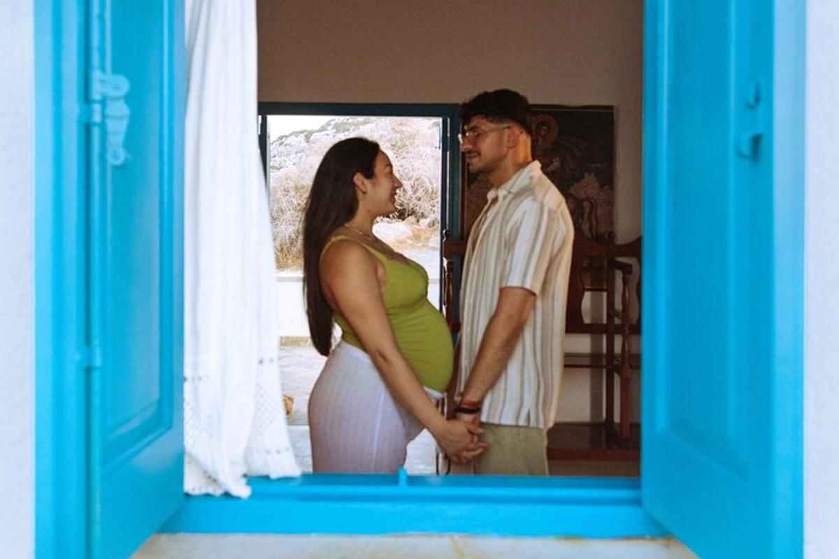 um homem e uma mulher grávida em pé em frente a uma janela