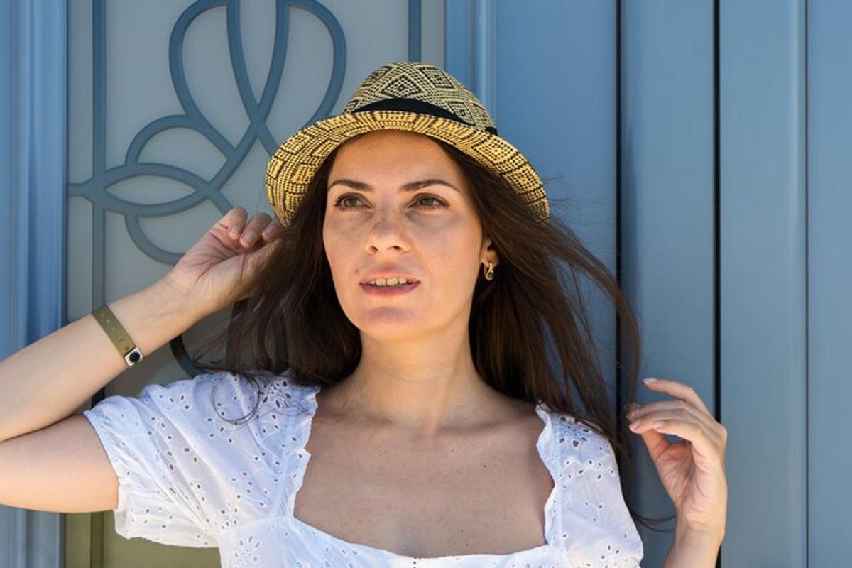 uma mulher usando um chapéu em pé em frente a um espelho