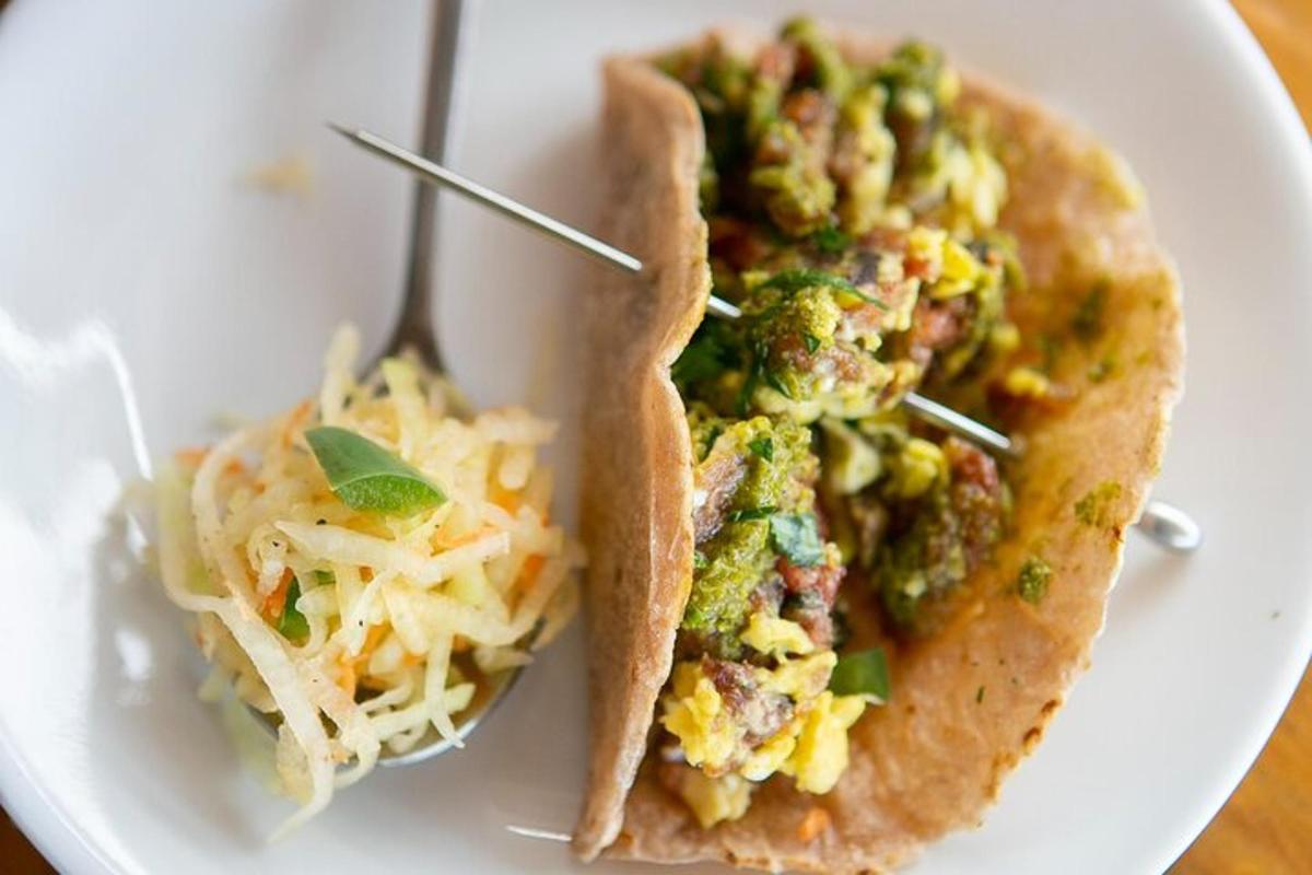 a white plate with two tacos with cheese and broccoli