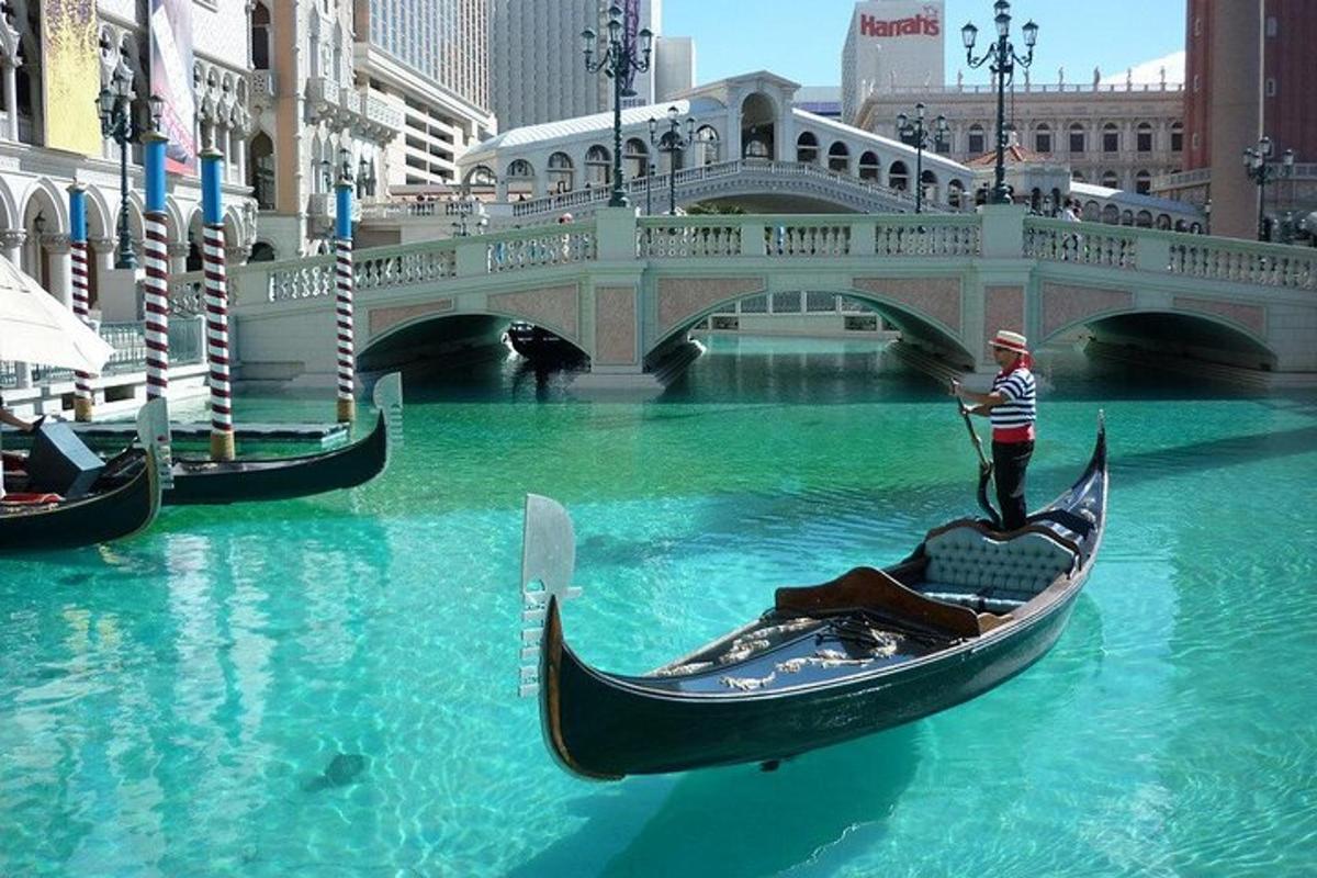 seorang lelaki menaiki gondola di dalam air berhampiran jambatan
