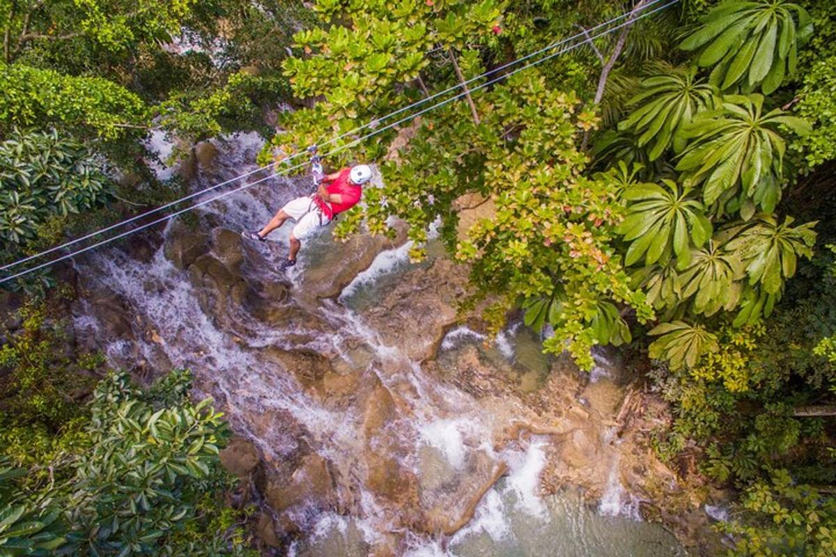 moški se spušča po ziplineu čez slap