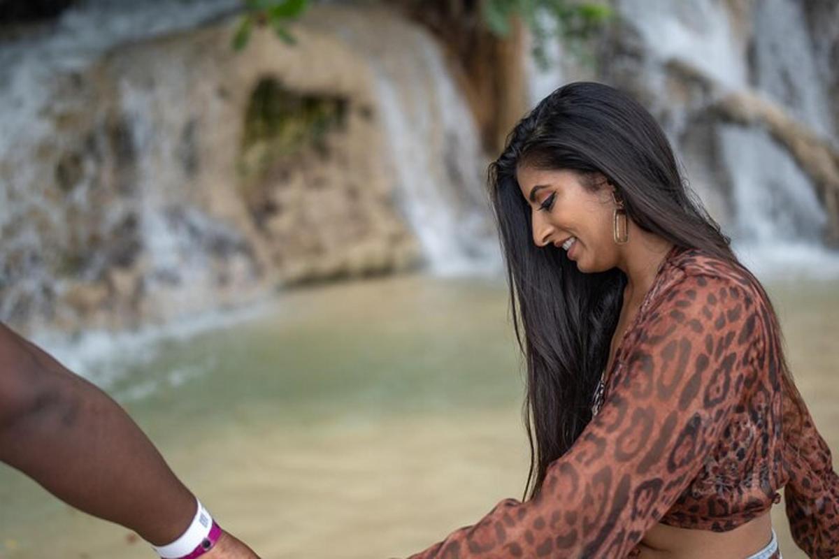 una donna con tatuaggi seduta davanti a una cascata