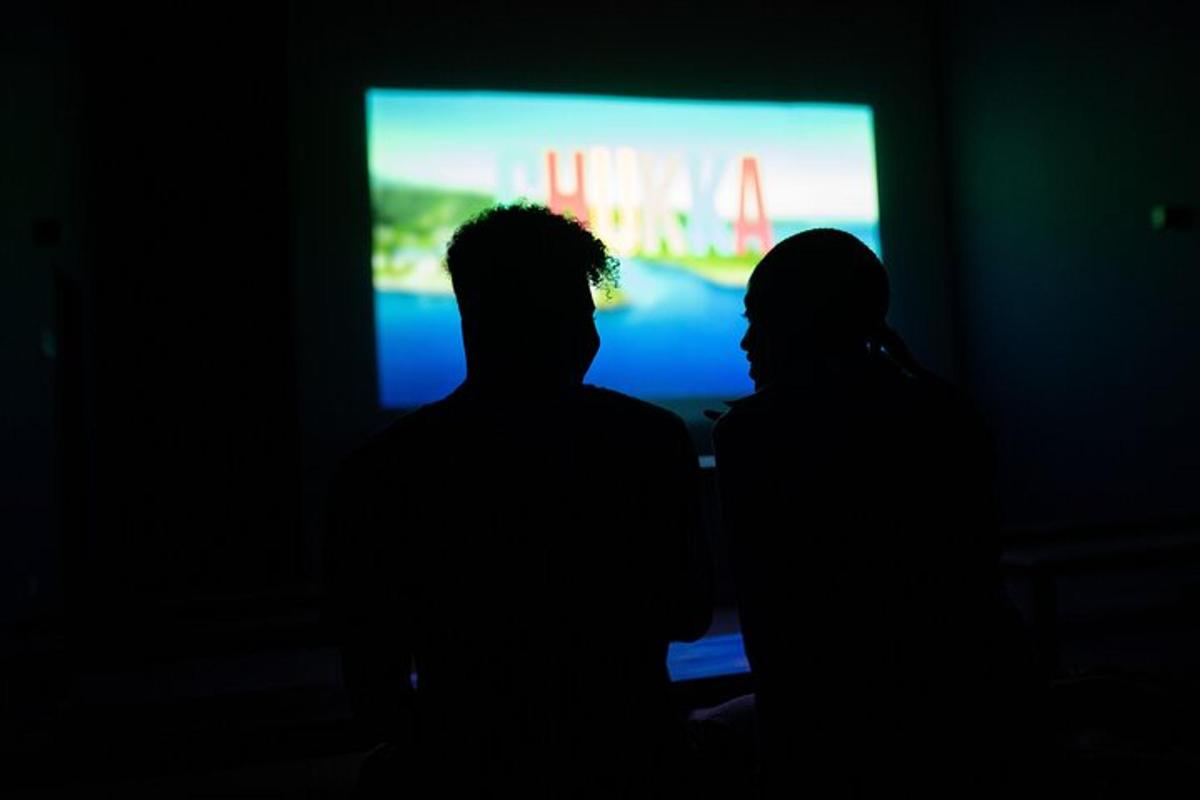 to personer står foran en TV i et mørkt rom
