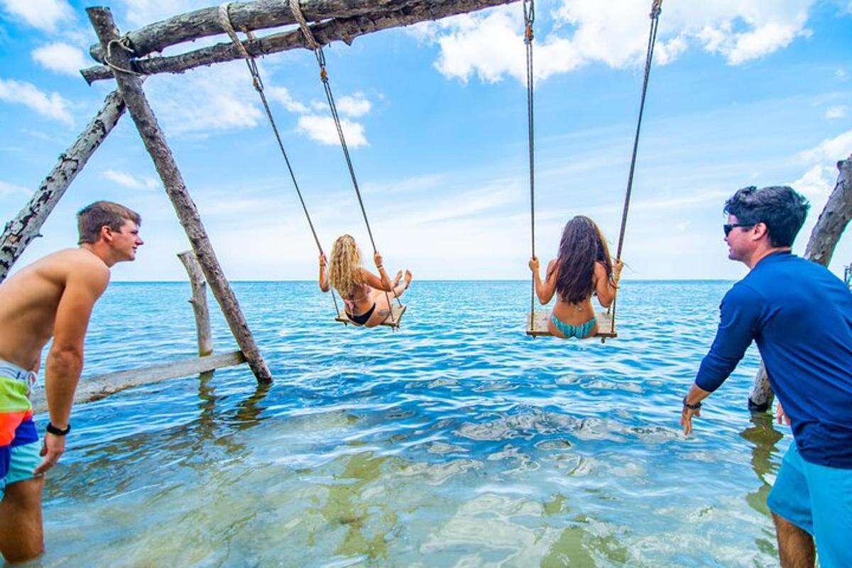 a group of people in the water on swings in the ocean