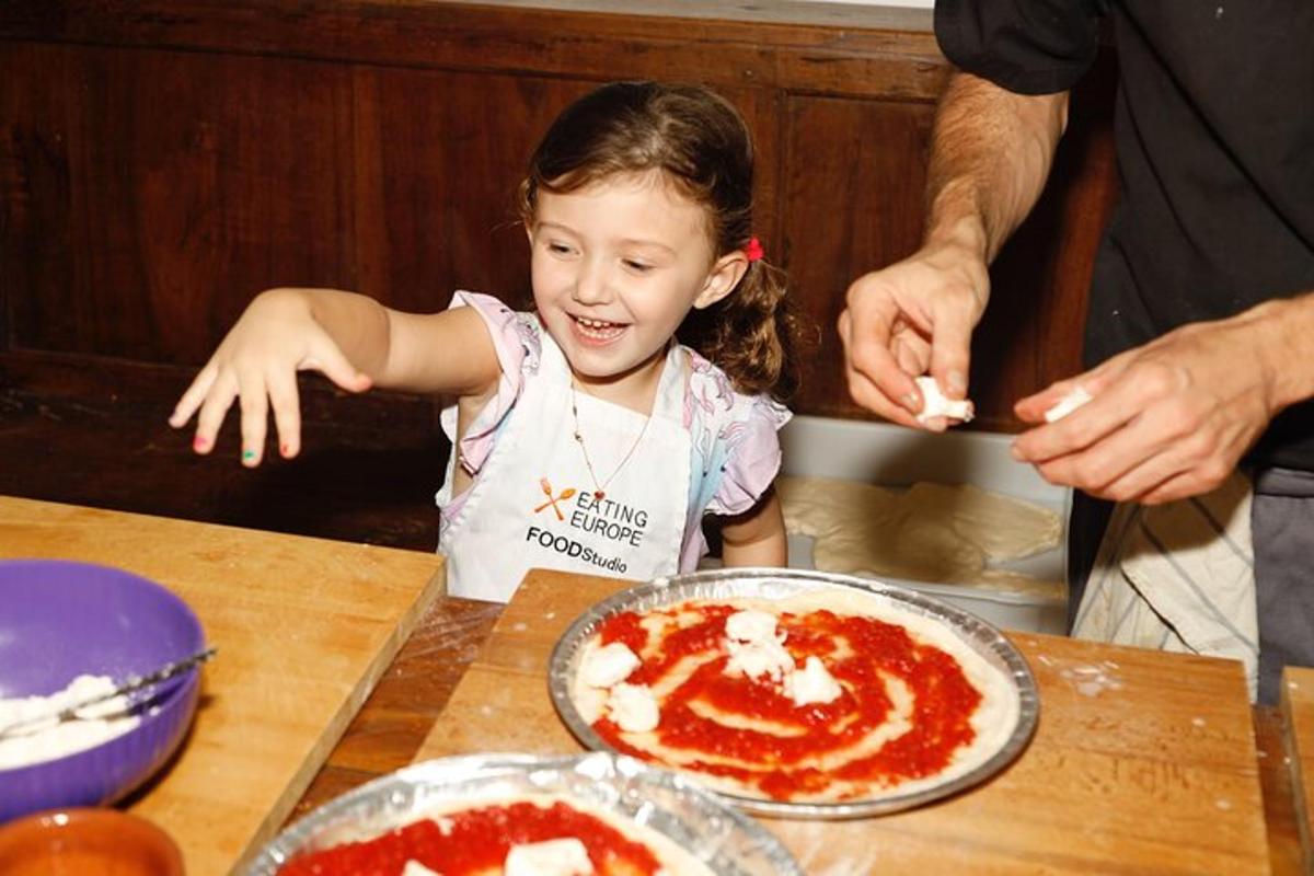 une petite fille assise à une table en train de faire une pizza