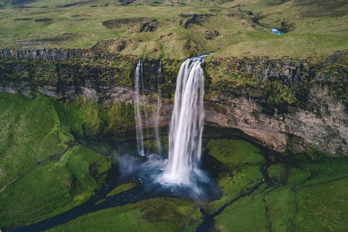 an aerial view of a waterfall on the side of a mountain