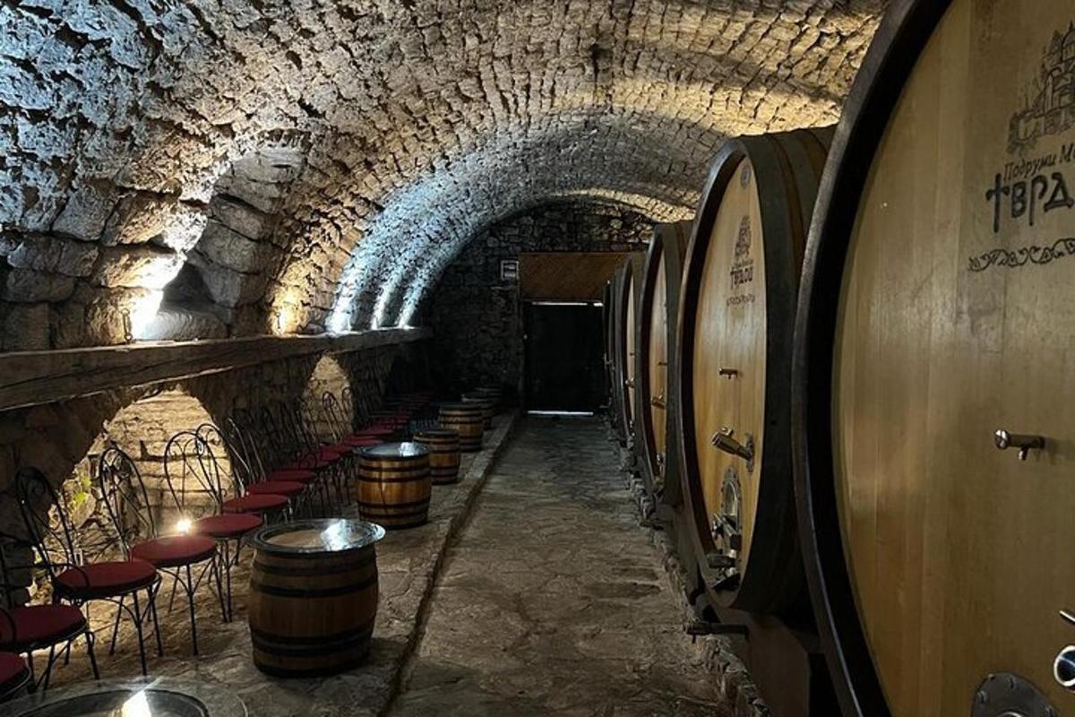 un tunnel con botti e sedie in una cantina vinicola