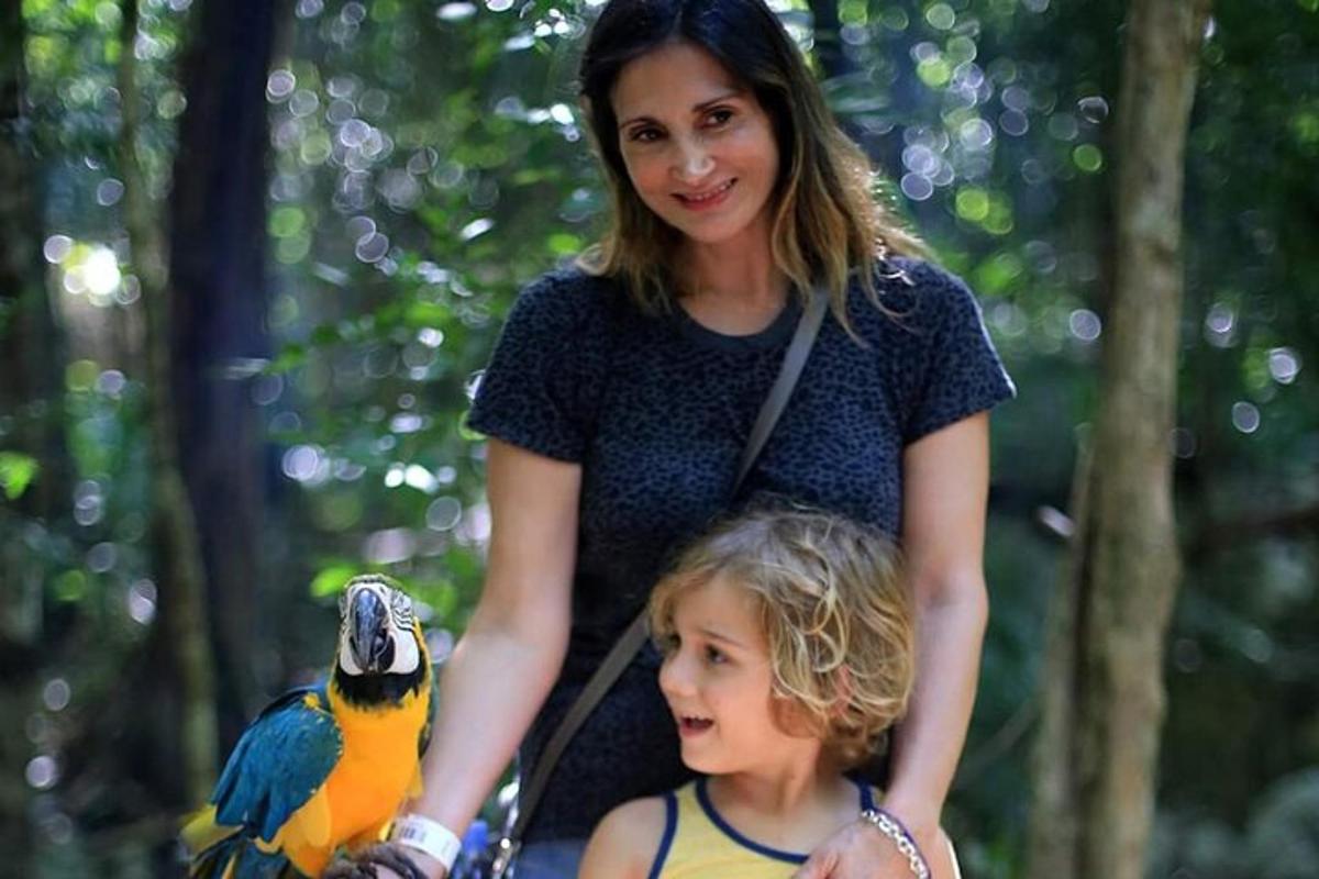 a woman and a child with a parrot on her arm