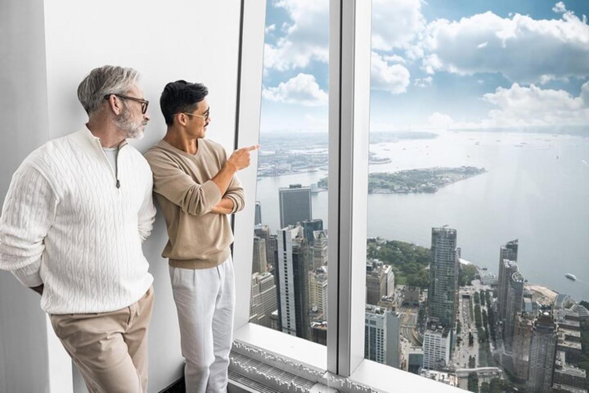 two men standing in front of a window looking at the city