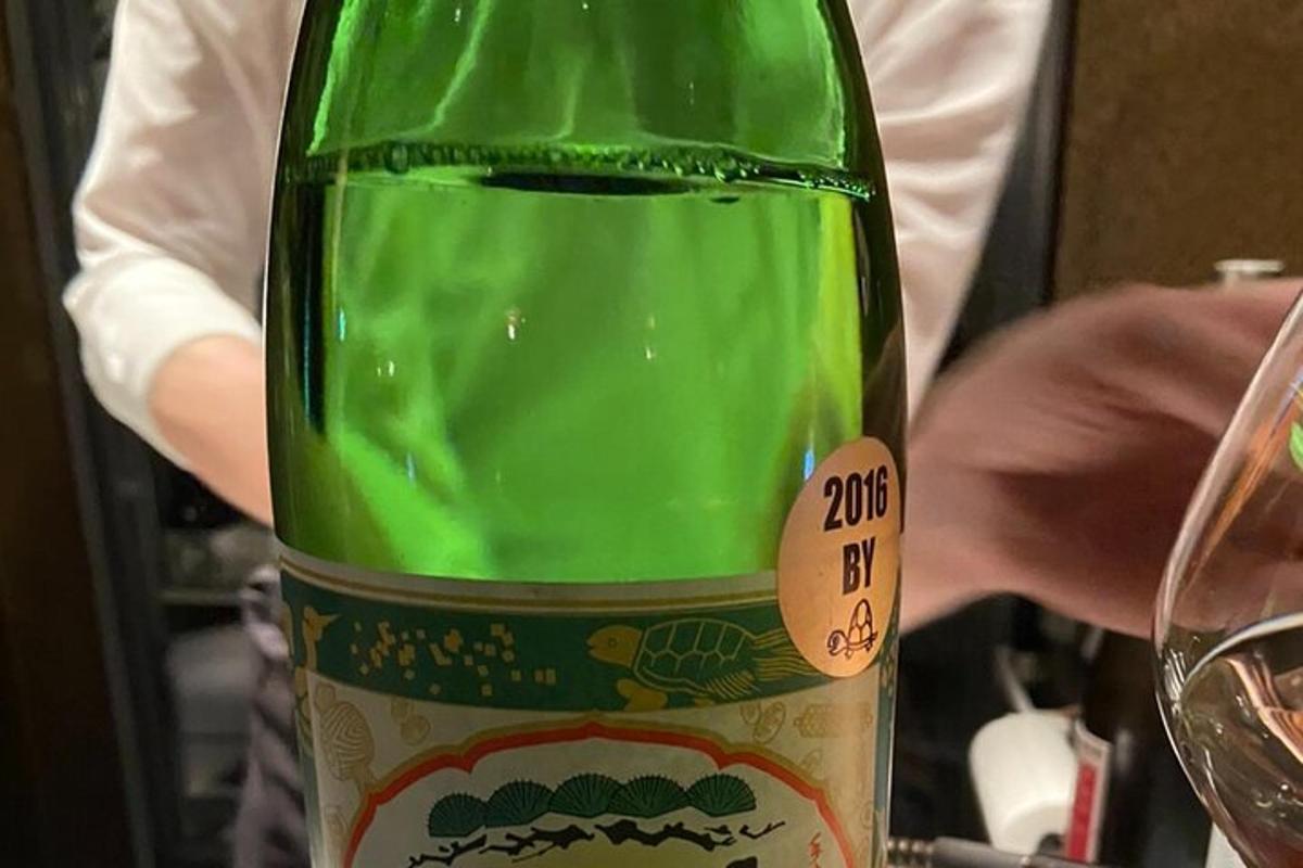 en grön flaska vin som står bredvid ett glas
