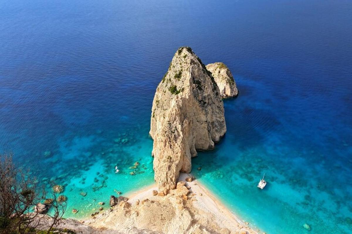 batu besar di lautan dengan bot di dalamnya