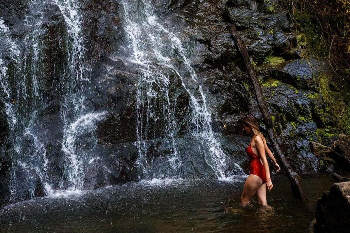 a woman standing in the water in front of a waterfall