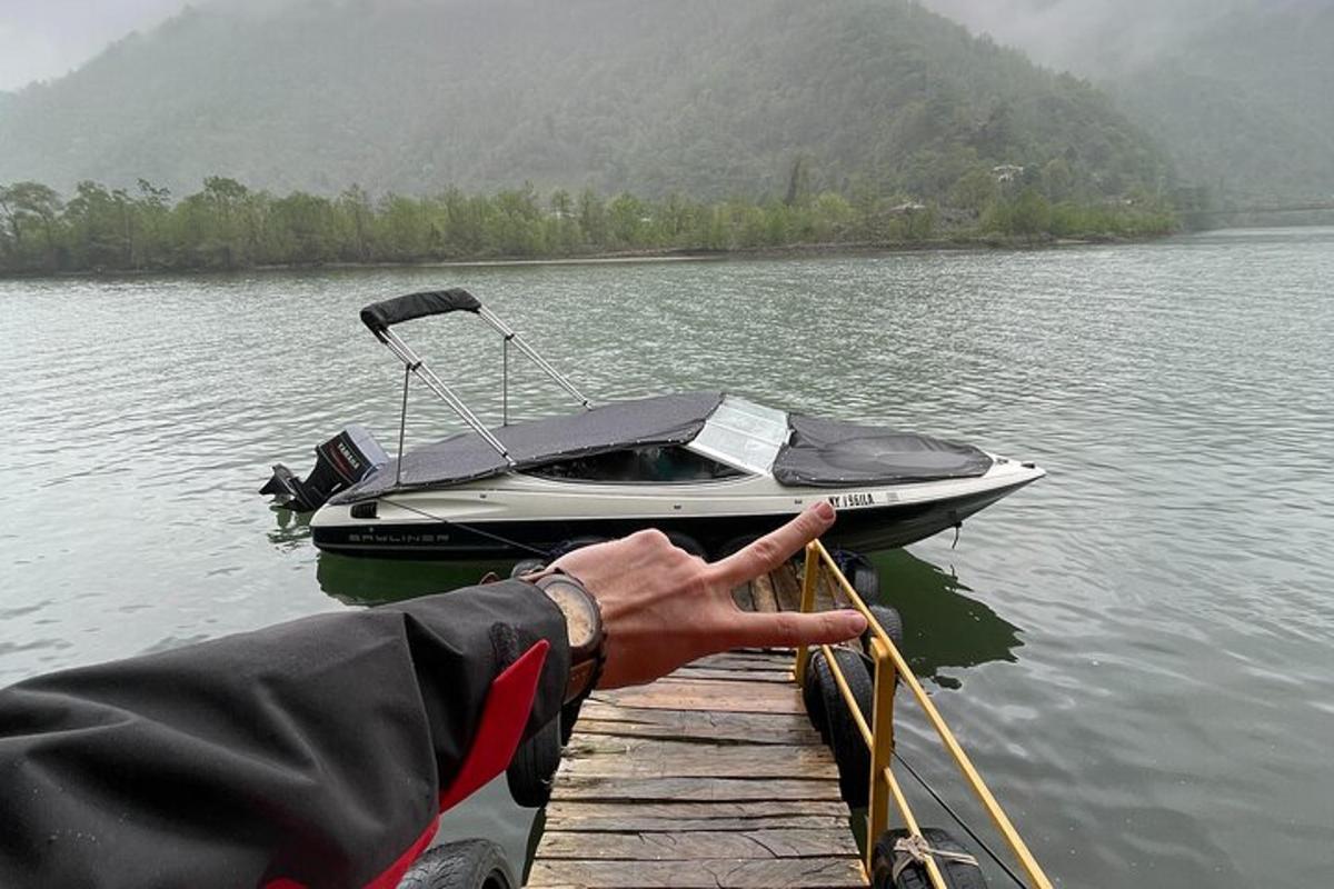 a person holding onto a dock with a boat on a lake