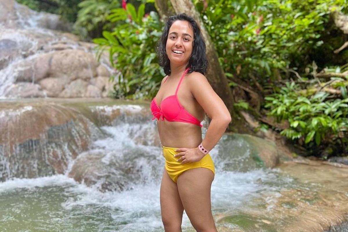 una donna in bikini in piedi davanti a una cascata
