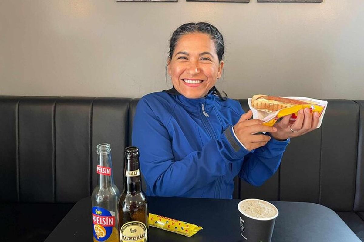 una donna seduta a un tavolo con in mano un hot dog