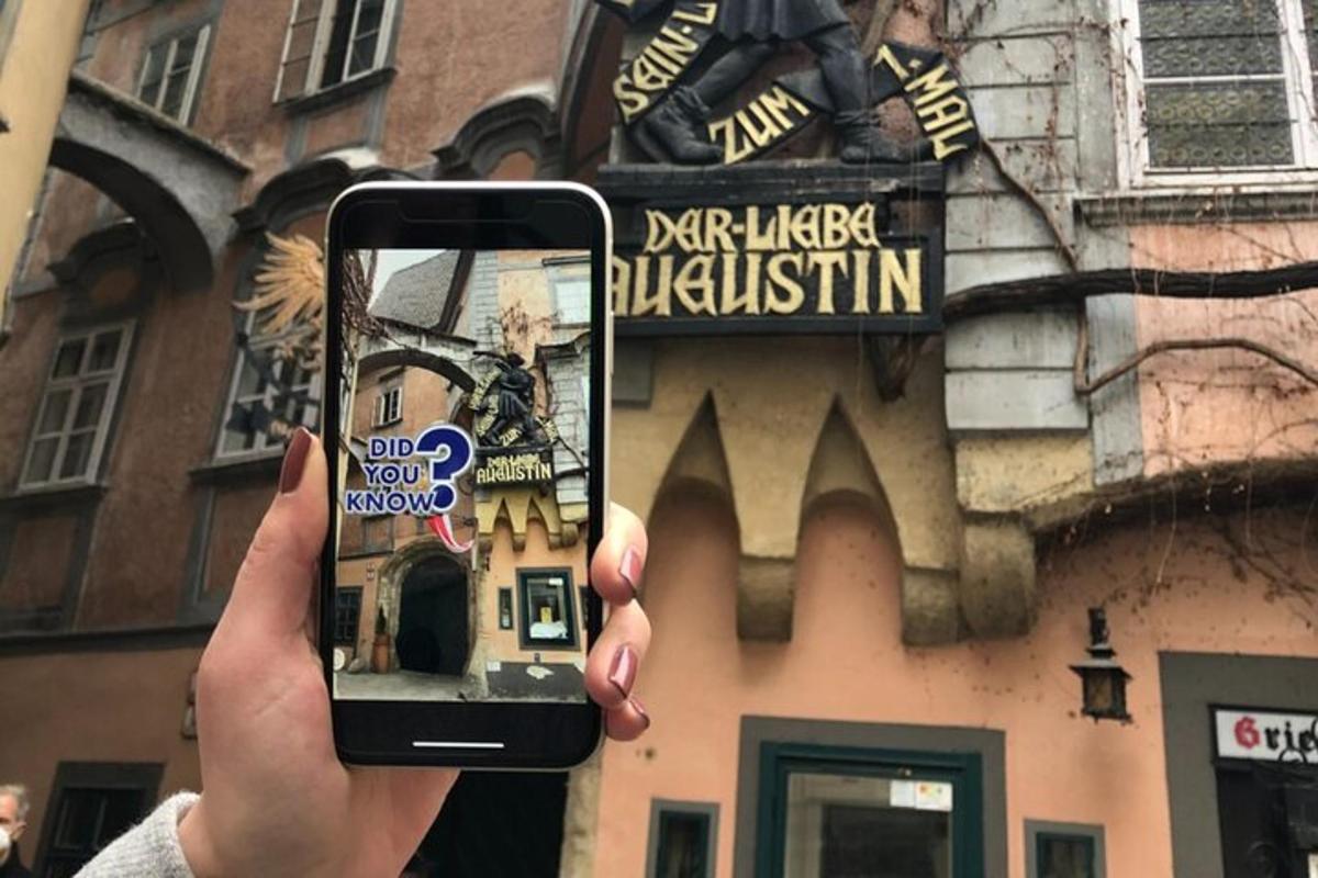 osoba držící mobilní telefon před budovou