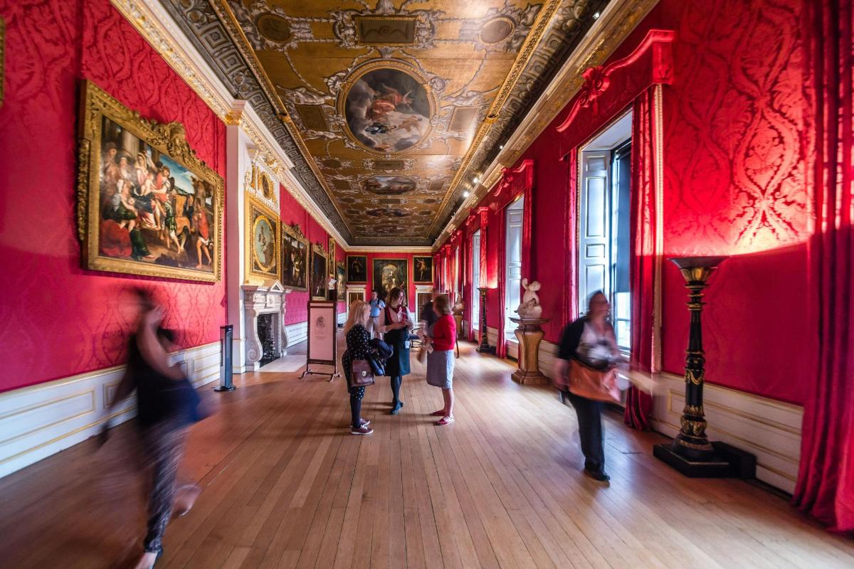 a group of people walking through a room with red walls