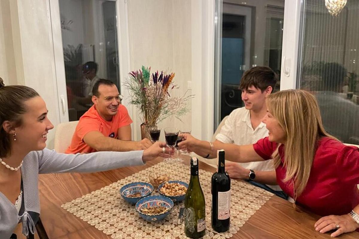 skupina lidí sedících kolem stolu a popíjejících víno