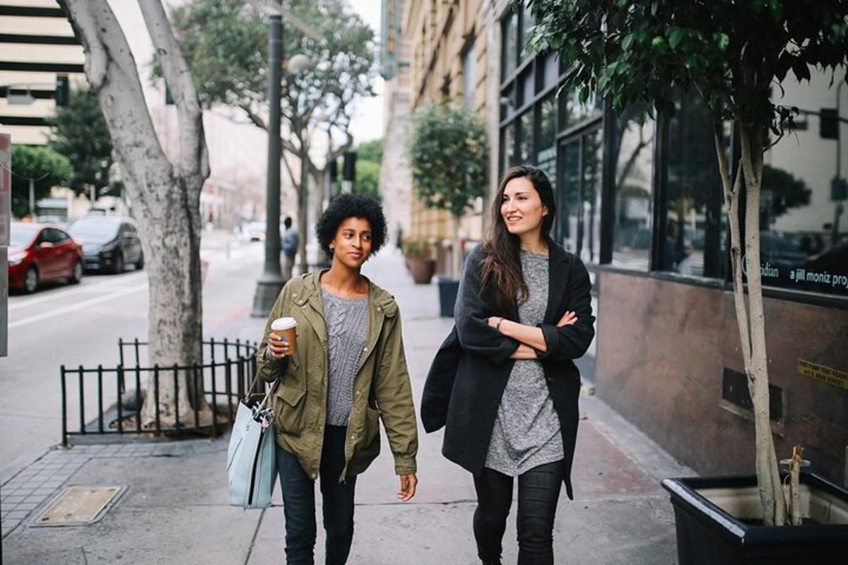 twee vrouwen lopen over een stoep op een stadsstraat