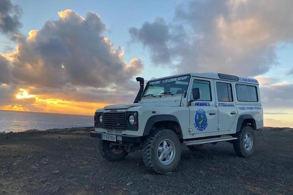 a white truck parked on the beach with the sunset