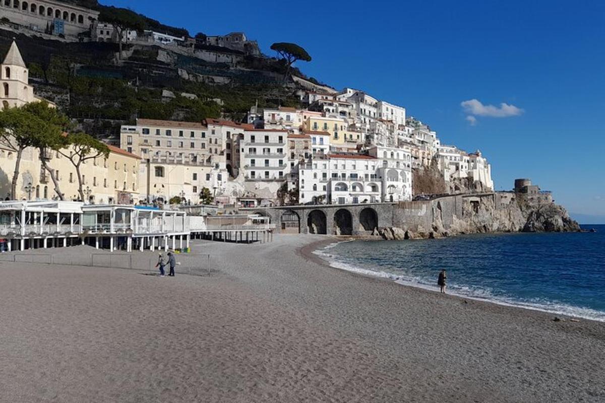 una platja amb edificis blancs en un turó al costat de l'aigua