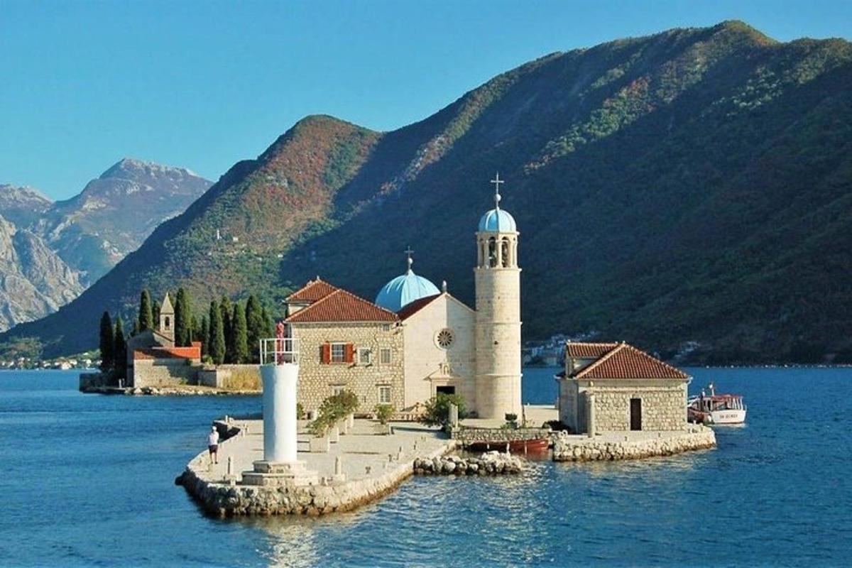 uma igreja em uma ilha na água com montanhas