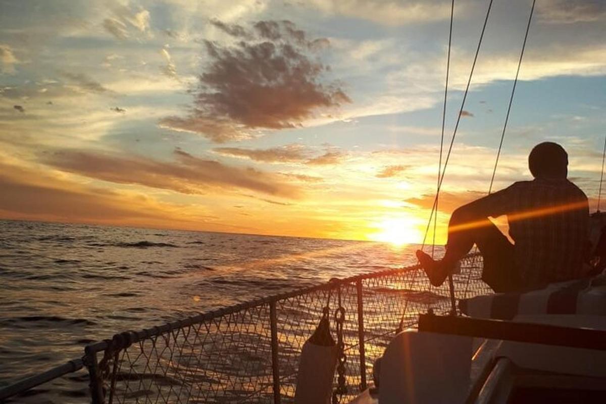 isang lalaking nakaupo sa bangka habang pinapanood ang paglubog ng araw