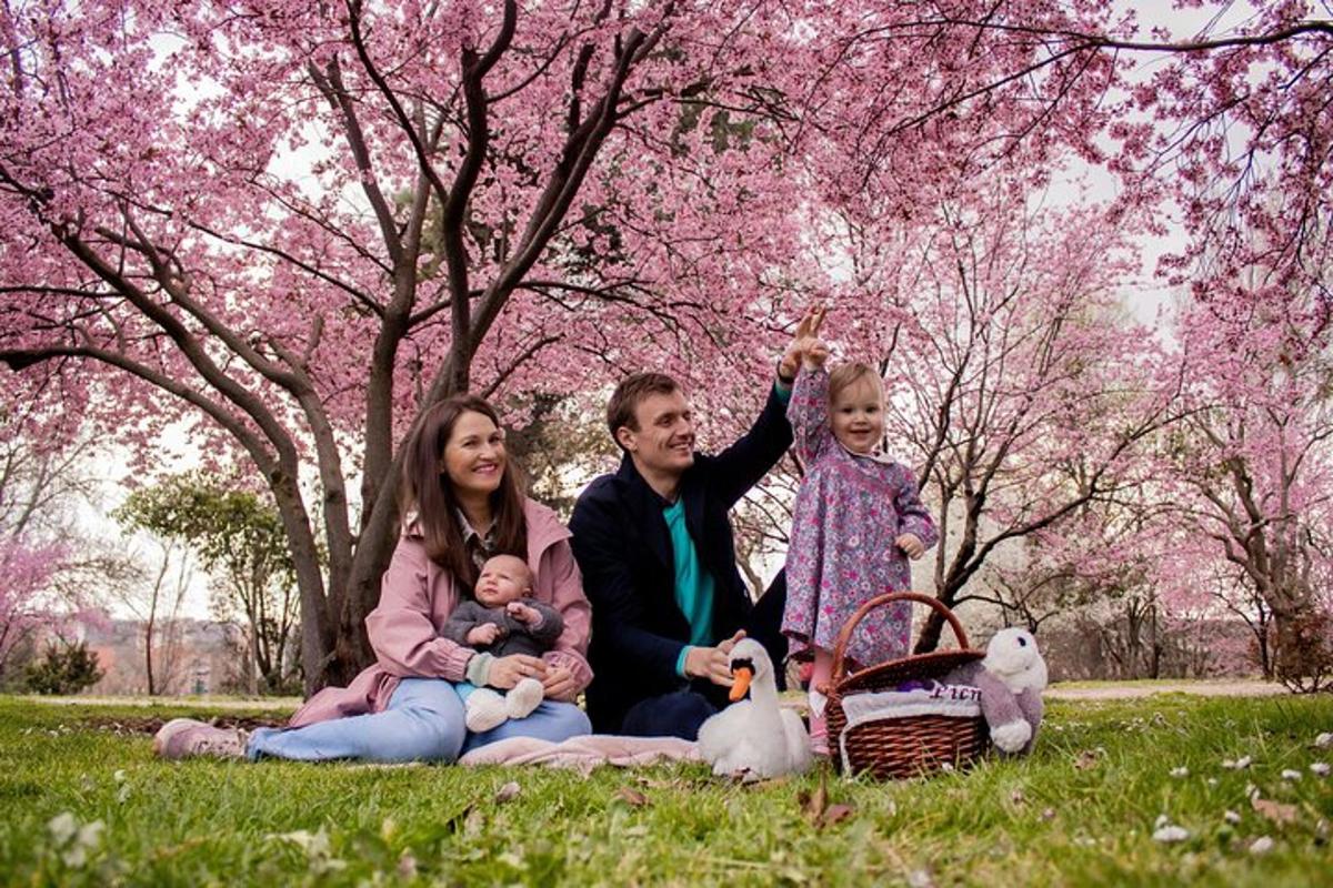 una família asseguda a l'herba davant d'arbres florits