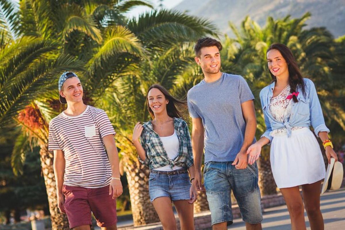 a group of people walking down a road with palm trees