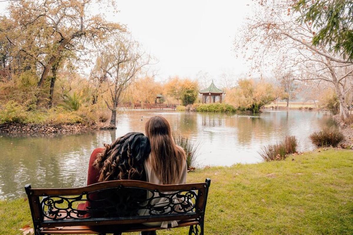 duas mulheres sentadas em um banco olhando para um lago