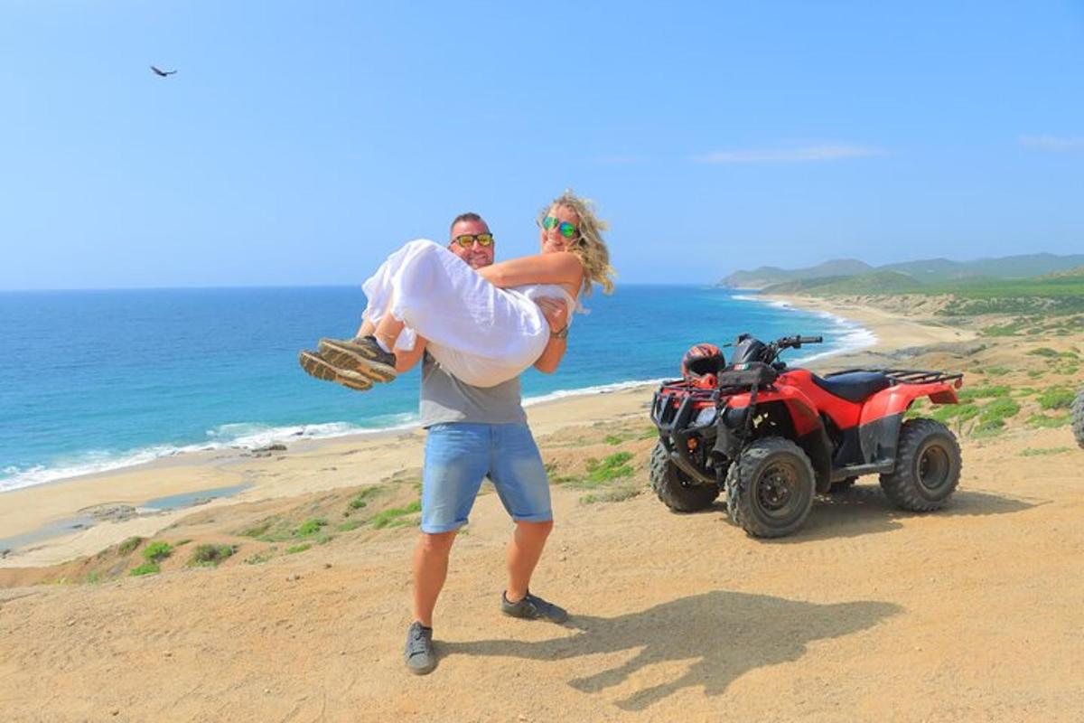 un home i una dona drets a la platja al costat d'un quad