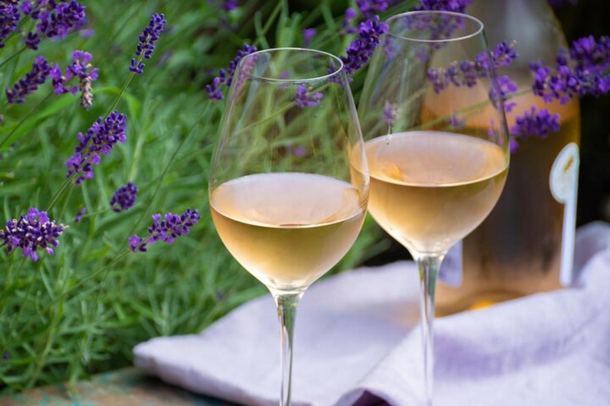 duas taças de vinho branco ao lado de flores roxas