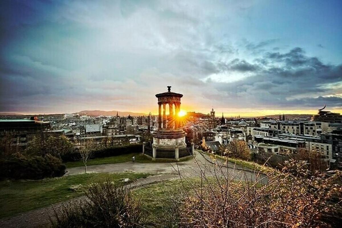 uma torre do relógio com o sol se pondo atrás de uma cidade