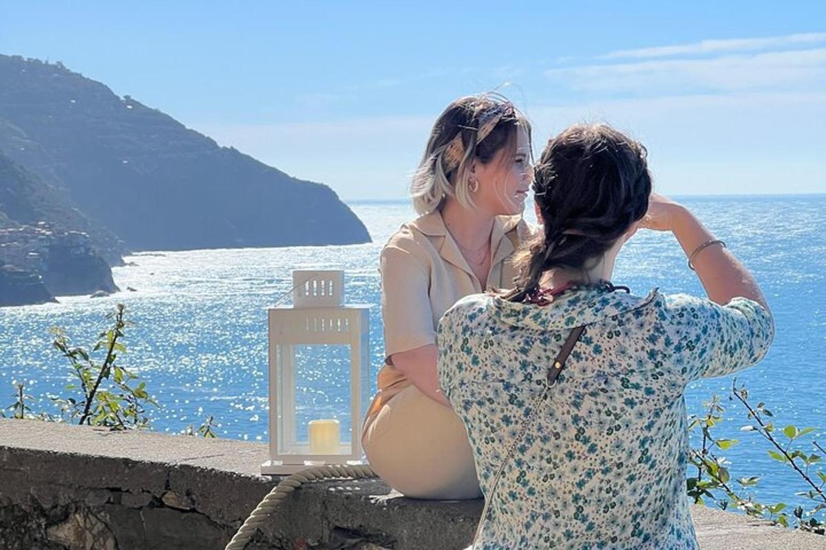 Dos mujeres sentadas en un muro mirando el océano