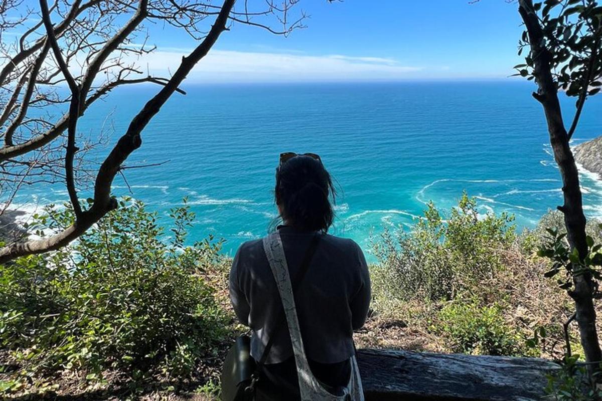 ženska, ki stoji na hribu in gleda na ocean
