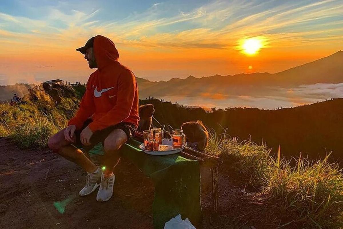 một người đàn ông ngồi trên đỉnh núi với một khay đồ uống