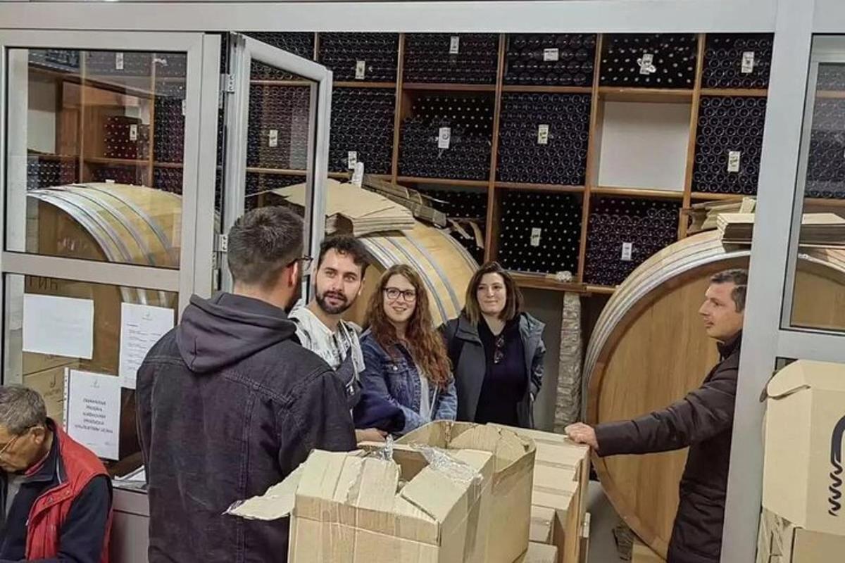 Skupina lidí stojících kolem krabic ve vinotéce