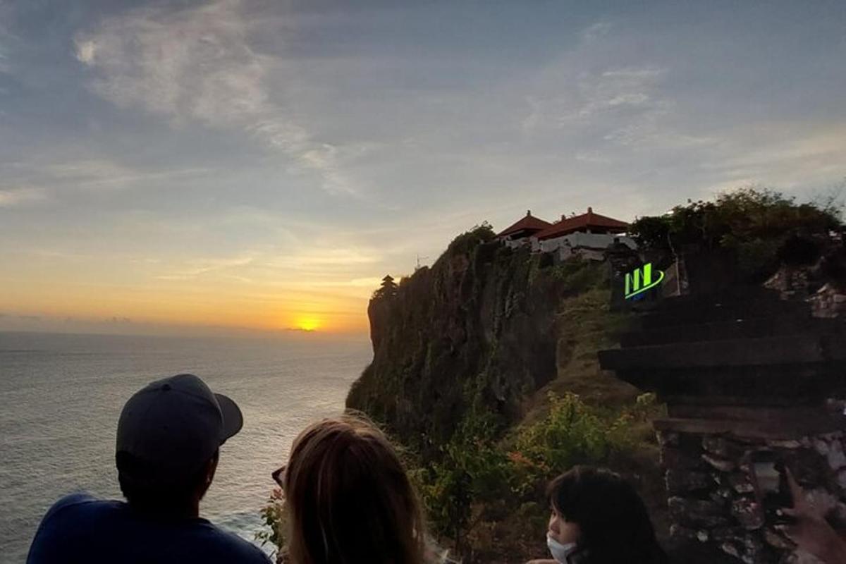 un grup de persones mirant la posta de sol en un penya-segat